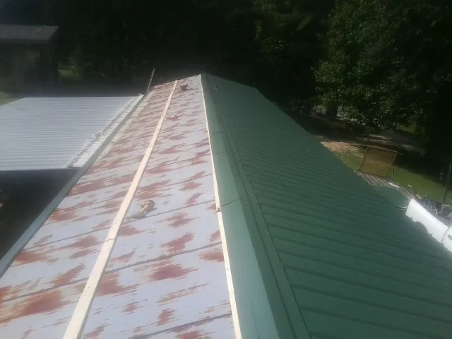 Old rusted panels beside newly installed green metal roofing — Wind Damage Roof Repair by Roofing Brothers in Emeryville