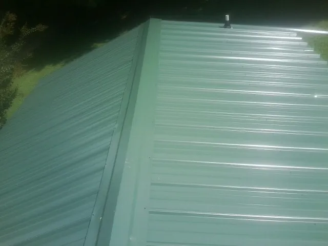New green metal panels meeting at the ridge of a roof — Flat Roof Repair work by our crew in Emeryville