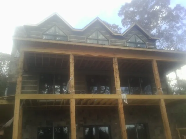 Dormers and porch framing on a large log home under construction — Roof Coating work by our crew in Emeryville