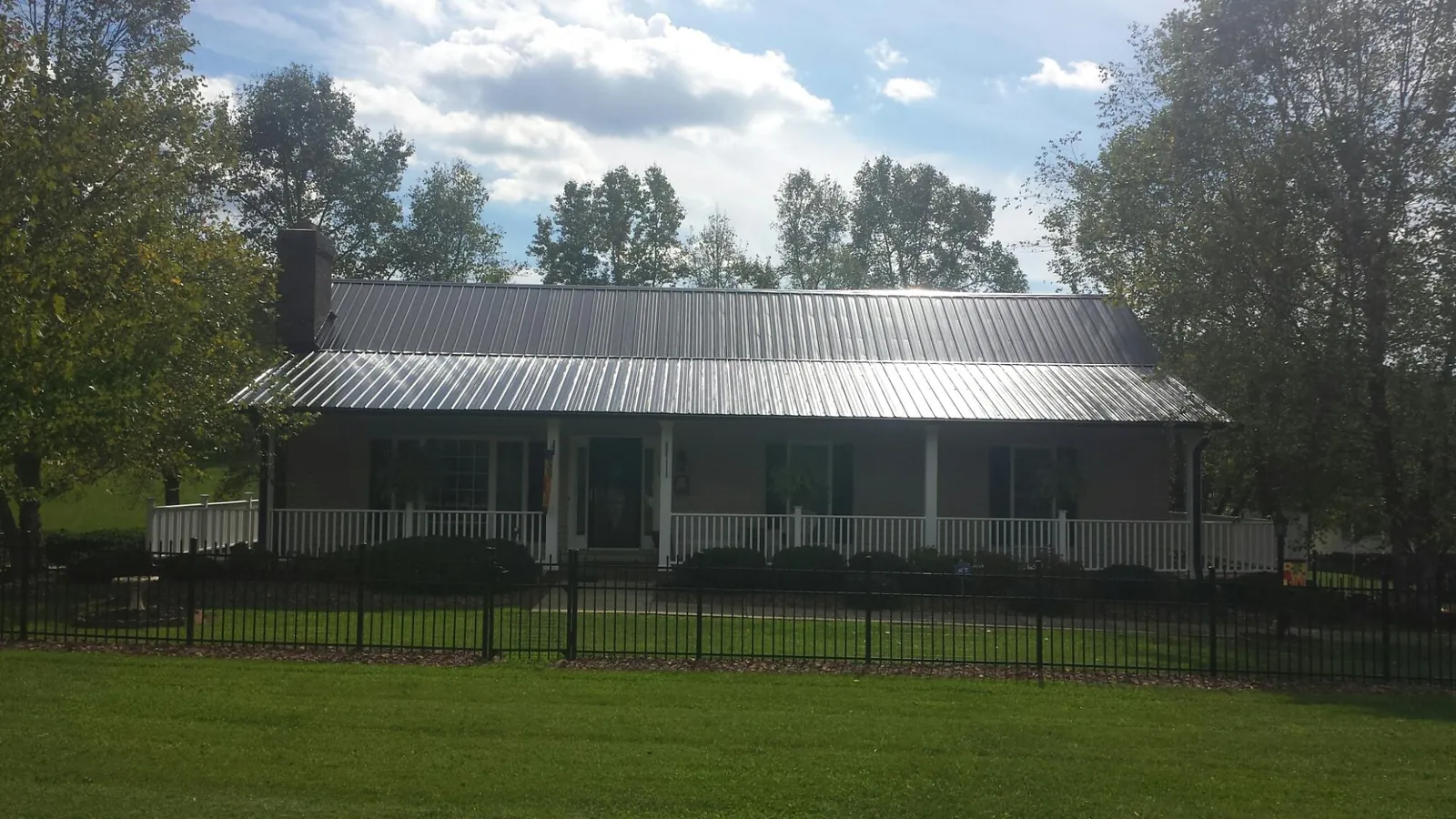 Gray metal roof on a brick ranch with a full width front porch — Gutter Guard Installation work by our crew in Emeryville
