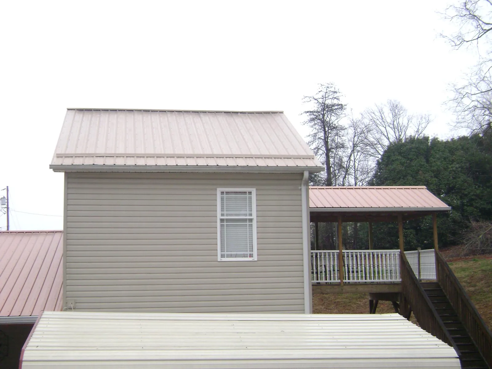 Tan metal roofs on a two story addition and attached porch, from a Roof Replacement job in Emeryville